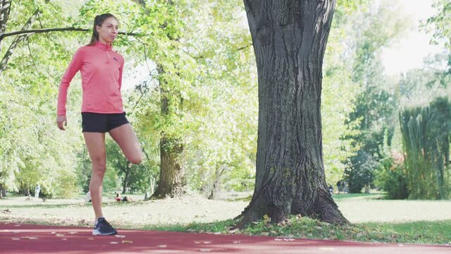 Runner girl stretching her body in the park. Warming up exercise for running