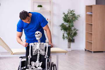 Young male doctor and skeleton in wheel-chair