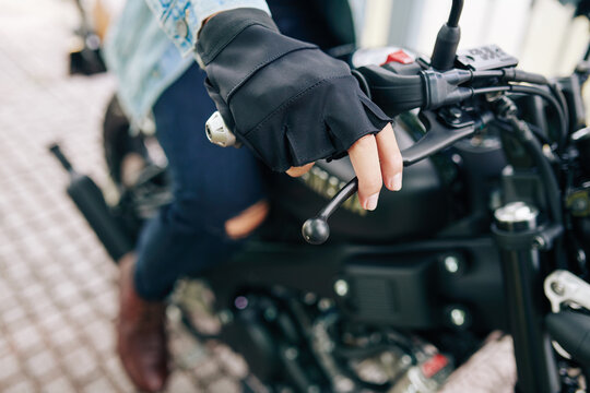 Close-up image of motorcyclist in leather fingerless gloves twisting grip toward him to start riding