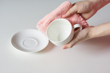 Close up woman hand cleaning coffee cup on the morning with microfiber cloth, Close up woman hand cleaning coffee cup on the rustic wood table.