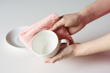 Close up woman hand cleaning coffee cup on the morning with microfiber cloth, Close up woman hand cleaning coffee cup on the rustic wood table.