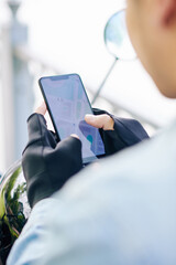 Close-up image of motorcyclist in leather fingerless gloves checking map on smartphone screen
