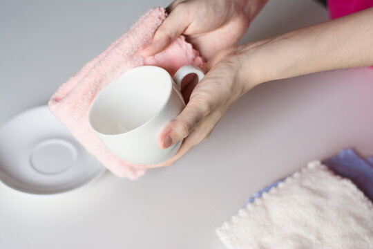 Close up woman hand cleaning coffee cup on the morning with microfiber cloth, Close up woman hand cleaning coffee cup on the rustic wood table.