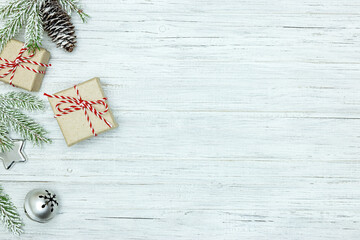 snowy christmas tree branch and handmade paper gift boxes on white wooden background