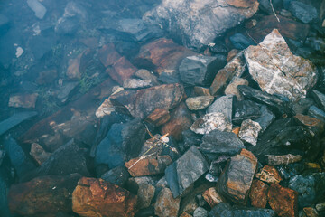 Nature background with many stones on bottom of mountain lake with clear water. Natural texture of stony lake bottom. Full frame of stone pile closeup in calm water. Rocks in transparent water.