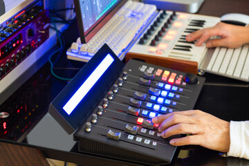 Sound engineer hands adjusting volume on digital audio control surface for mixing audio tracks on computer. Post production, broadcasting, recording concept