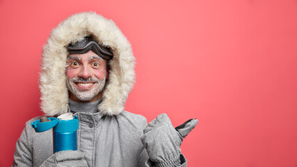 Cheerful bearded male skier with happy expression enjoys winter recreation dressed in warm jacket...