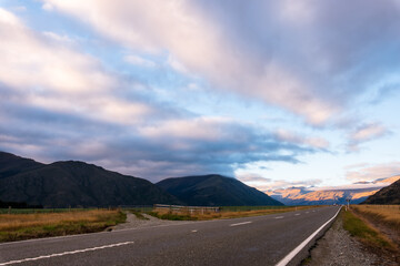A long straight road with raining cloud and Mountain in evening
