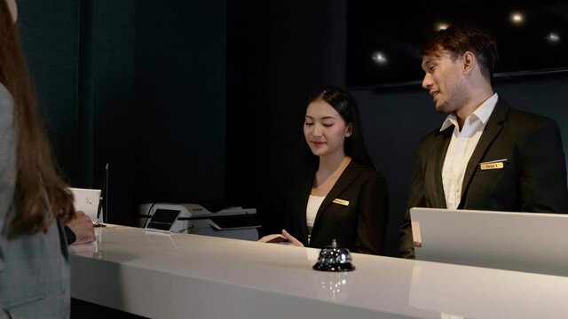 couple celebrating their anniversary checking in at hotel reception female receptionist asking for and checking their passports . He receives a key card from the room, business trip..