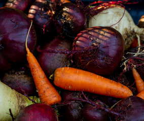 background of fresh carrots with tops and beets with soil from the garden with harvesting in autumn