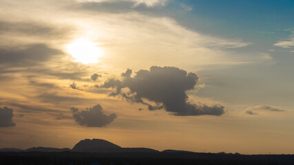 Silhouette of hills against beautiful golden hour light with wide angle and beautiful clouds formation and a glimpse of blue sky