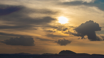 Silhouette of hills against beautiful golden hour light with wide angle and beautiful clouds formation and a glimpse of blue sky