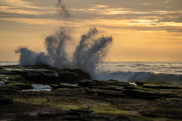 waves smashing against rocks at sunrise