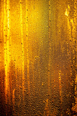 Drops of water on the glass of the window at sunrise as a background.