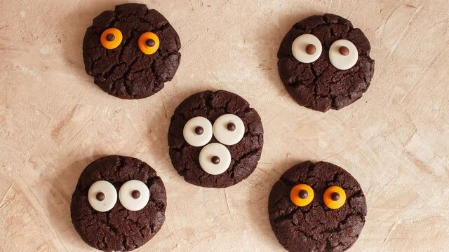 Halloween cooking recipes. Сhocolate chip cookies decorated with chocolate eyes. Festive Halloween cookie. Delicious spooky halloween baking. Stop motion animation, top view
