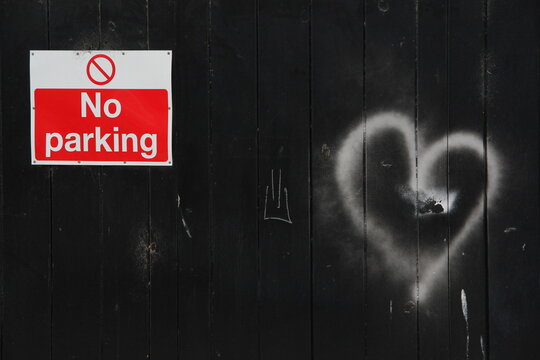 no parking sign on a black garge door with white love heart shape