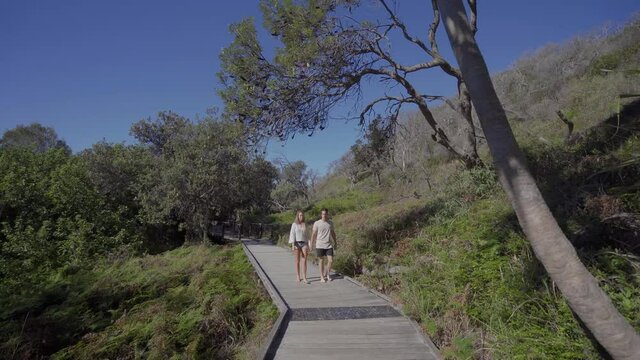 Young Couple Walking on nature boardwalk at Eli Creek, Fraser Island - super wide shot tracking backwards