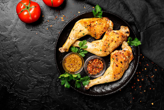 Grilled chicken legs with spices on black background. top view