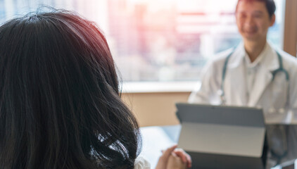 Professional medical doctor in white uniform gown coat interview counseling female patient: Physician writing on patient chart while consultation: Hospital/ clinic healthcare professionalism concept