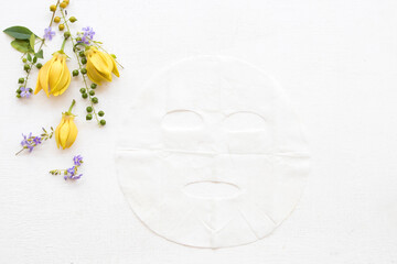 natural aroma sheet mask for skin face from herbal ylang ylang yellow flowers essence face mask on background white