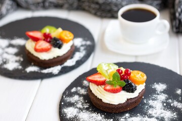 Chocolate cupcakes with cream cheese, fruits and berries. Mini cakes with custard cream. Coffee dessert
