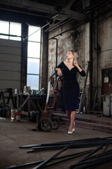 Fototapeta na wymiar Portrait of a blonde woman wearing black dress with a trolly in an old spooky factory