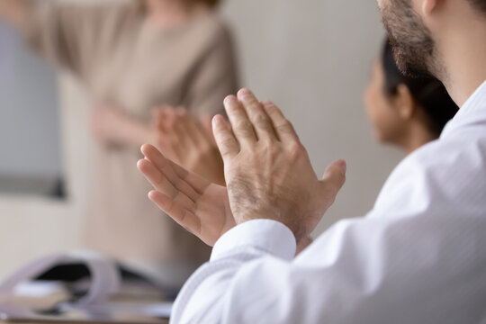 Crop close up of diverse employees applaud celebrating company business success at meeting. Excited workers clap hands greeting thanking coach or trainer for presentation. Acknowledgement concept.