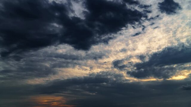 beautiful sunset sky time lapse, bright sun and dark silhouette of clouds as a background