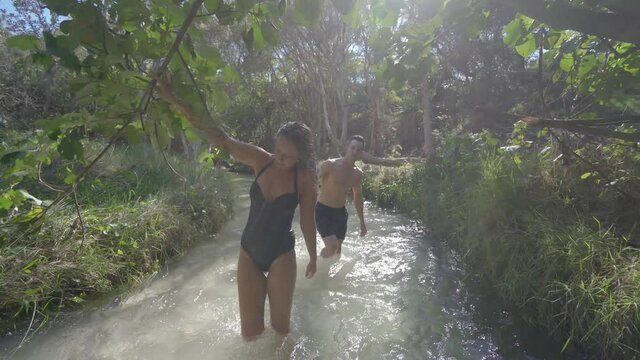  Young Couple wading in water stream surrounded by forest at Eli Creek, Fraser Island - wide tracking back - 03