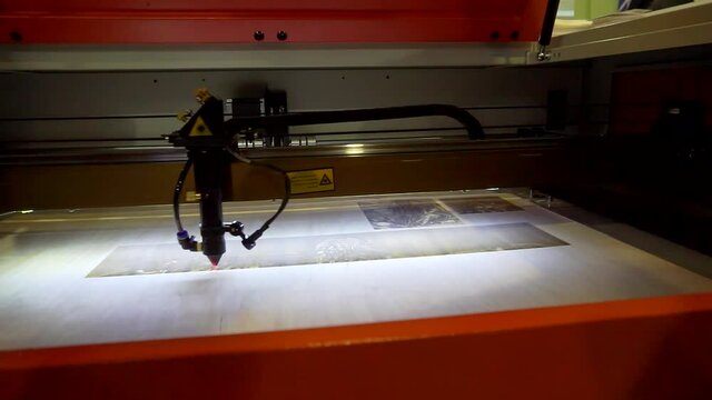 3D printer laser beam burns the pattern close-up on a wooden board.