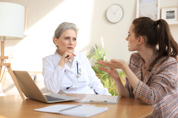 Middle aged female doctor therapist in consultation with patient in office.