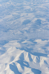 Aerial view of snow-capped mountains. Winter snowy mountain landscape. Skalisty peak, Icheghem Range, Kolyma Mountains. Koryak Okrug (Koryakia), Kamchatka Krai (region), Siberia, Far East of Russia.