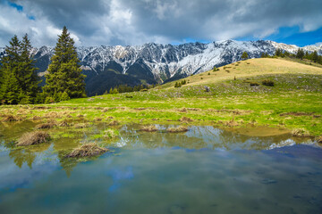 Small lake and snowy mountains in background, Piatra Craiului, Romania