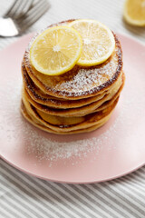 Homemade Lemon Ricotta Pancakes on a pink plate, low angle view.