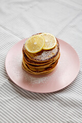 Homemade Lemon Ricotta Pancakes on a pink plate, side view.