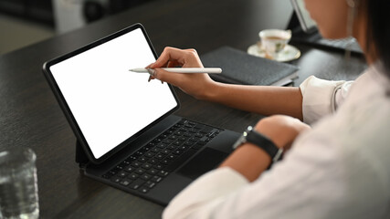 A young businesswoman using stylus pen pointing on screen digital tablet while sitting in office.