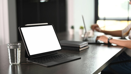 Stylish workspace with with screen computer tablet, water glass and notebooks.