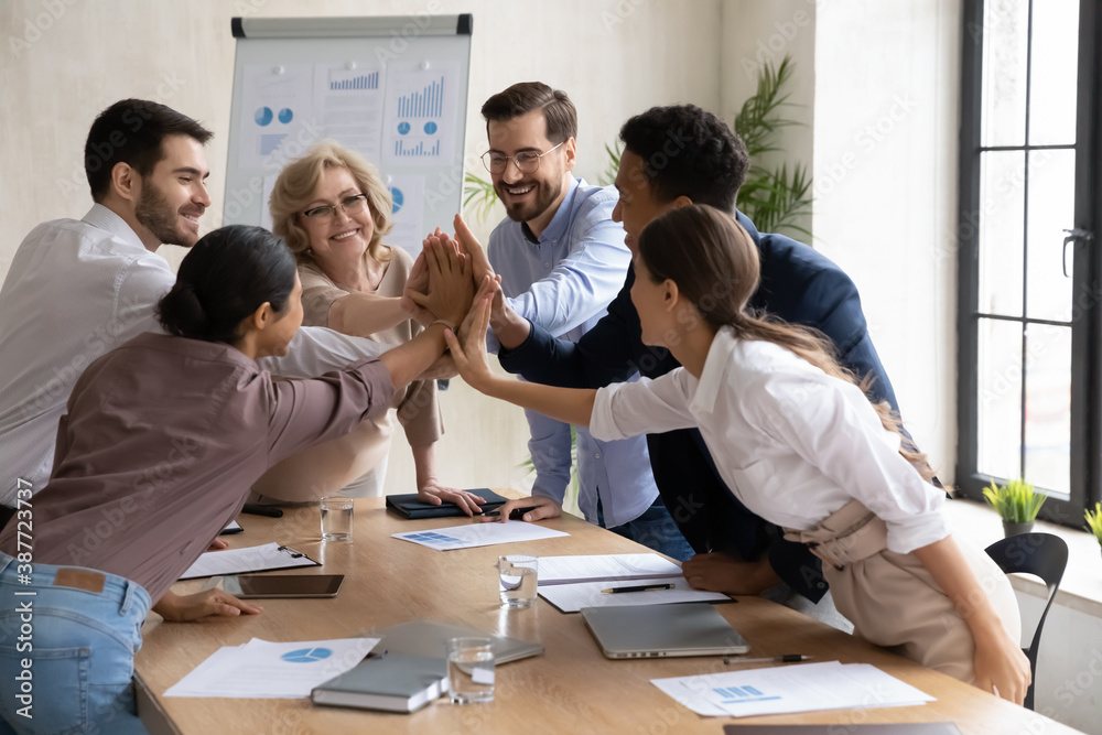 Wall mural overjoyed diverse businesspeople five high five motivated for shared business victory success or win