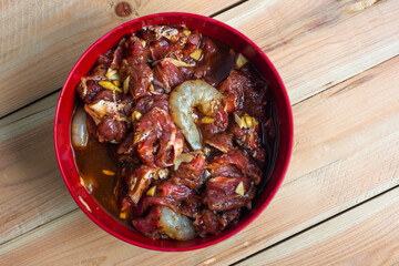Marinated beef in a bowl with wood background