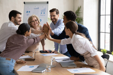 Overjoyed diverse businesspeople five high five motivated for shared business victory success or...