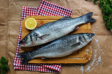 Two raw fish on a cutting Board decorated with a lemon slice close-up.Texture or background
