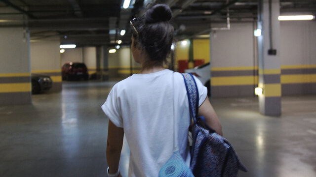 Teenager Sport Girl Walking Inside Parking Garage. Woman Holding Backpack And Yoga Mat. Urban City Lifestyle Outdoors Concept