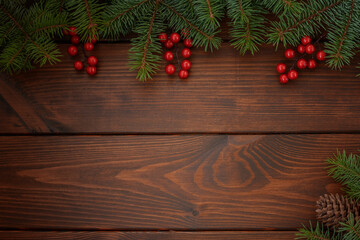 Fototapeta na wymiar Pine branches with cones and red berries on a wooden background. Christmas background. Happy New Year! Copy space for your text.