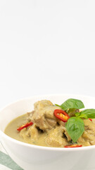 Traditional Thai cuisine, green curry chicken in white bowl over white background