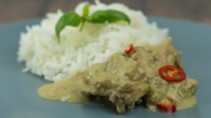 Traditional Thai cuisine, green curry chicken in white bowl over wooden background