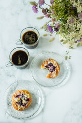 Flat lay photo of coffee cups, buns and wildflower bouquet