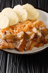 Vepro knedlo zelo is the national dish of Czechia the entree is made of pork loin and served over sauerkraut with a side of the Czech  boiled bread dumplings called knedlíky close-up in a plate
