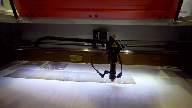 Laser engraving on wood. Laser printer moves on a wooden surface.