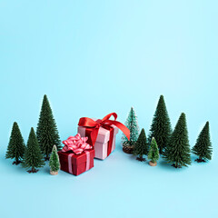 Christmas scene made with miniature pine trees, wrapped gifts and ornaments on blue background. Minimal New Year celebration or winter season concept. Greeting card.