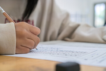 student taking notes lecture in high school or university with holding pencil writing on paperwork sheet and taking final exam in examination classroom